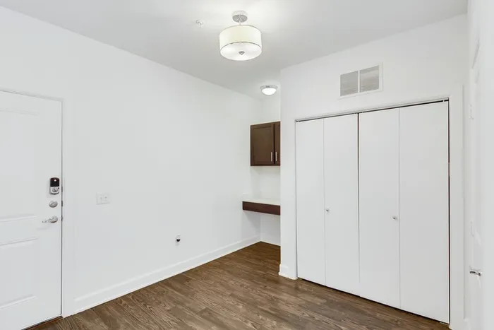 Spacious room with closet access, office access, white walls and wood flooring at Lantower Ambrosio Apartments