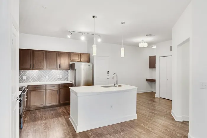 Modern kitchen equipped with stainless steel appliances, large countertops, a floating island, and ample lighting at Lantower Ambrosio Apartments.
