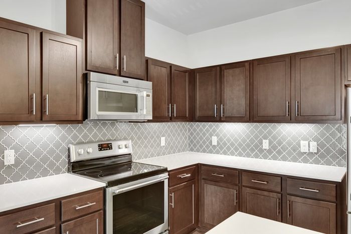 Modern kitchen equipped with stainless steel appliances, large countertops, a floating island, wood cabinets, and ample lighting at Lantower Ambrosio Apartments.