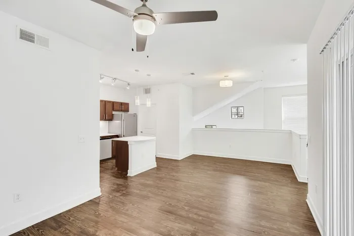 Spacious living room with ample room for seating, natural sunlight, and classic finishes with access to modern kitchen equipped with stainless steel appliances, large countertops, a floating island, and ample lighting at Lantower Ambrosio Apartments