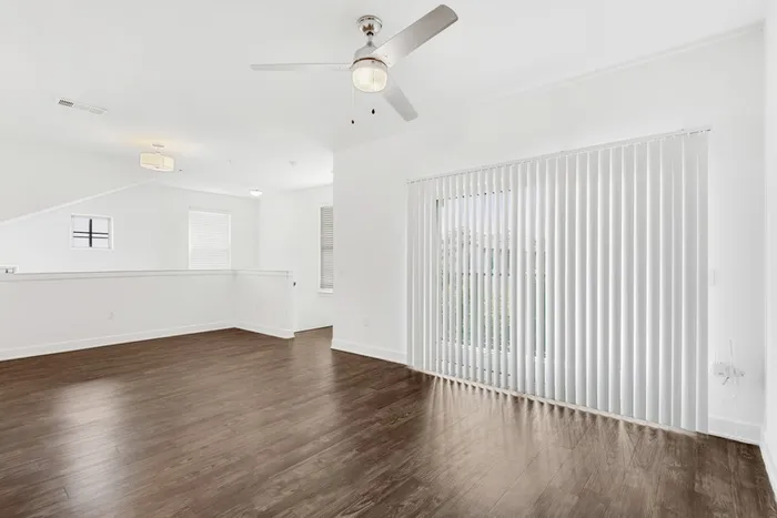 Spacious living room with ample room for seating, natural sunlight, and classic finishes, with access to private patio and stairs headed down at Lantower Ambrosio Apartments