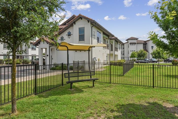 Outdoor relaxation area with plenty of space for outdoor activities, with a park bench and shade cover at Lantower Ambrosio Apartments