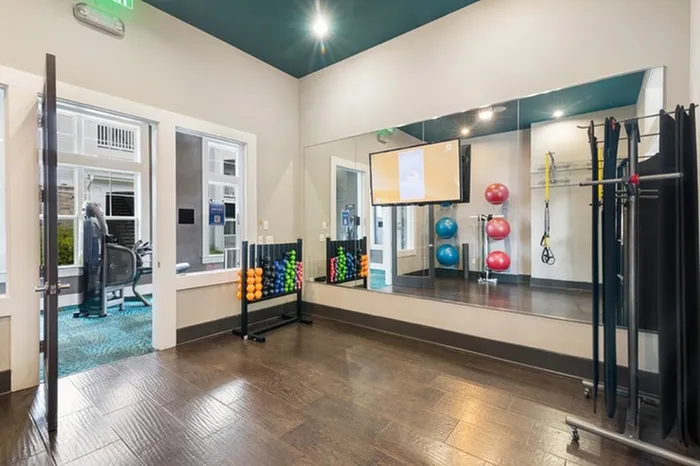 Yoga studio with wood-style flooring and wall mirrors at Patterson Place Apartments.