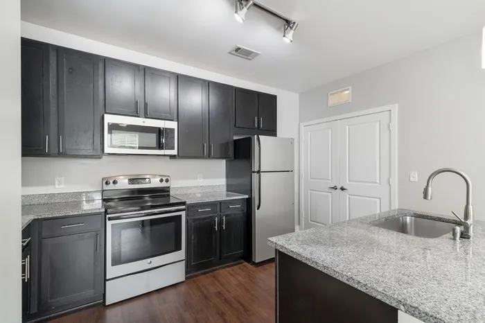 Energy-efficient kitchen with granite countertops, stainless steel appliances, and a kitchen island at Realm at Patterson Place.