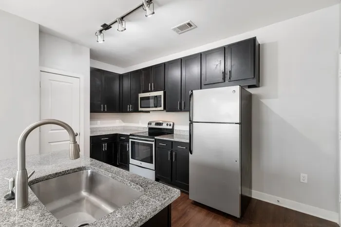 Energy-efficient kitchen with granite countertops, stainless steel appliances, and a kitchen island at Realm at Patterson Place.