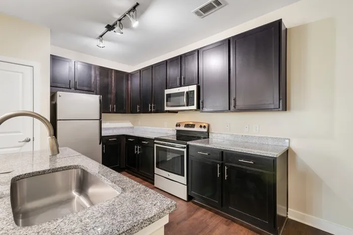 Energy-efficient kitchen with granite countertops, stainless steel appliances, and a kitchen island at Realm at Patterson Place.