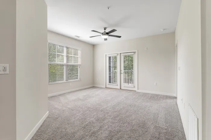 Carpeted living room with a large window and access to a bathroom at Realm at Patterson Place.