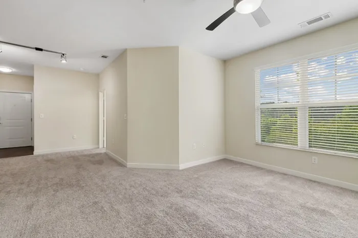Carpeted living room with a large window and access to a bathroom at Realm at Patterson Place.
