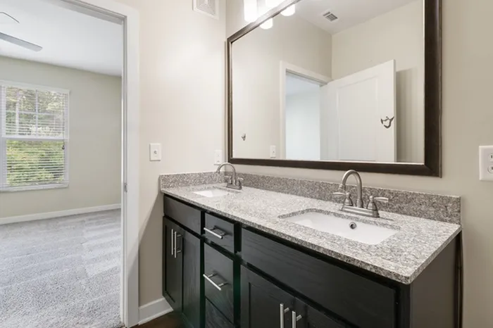 Bathroom with grey, granite countertops, and dark-colored cabinetry at Realm at Patterson Place.