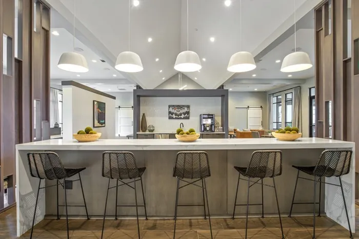 Clubhouse with modern, leather-style seating, wood-style floors, TVs, and ample natural sunlight at Lantower Garrison Park.