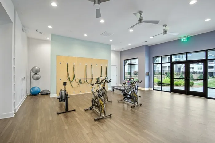 Lantower Garrison Park's 24-Hour Fitness Center with Yoga Room & Fitness On-Demand with wooden floors and floor-to-ceiling windows.
