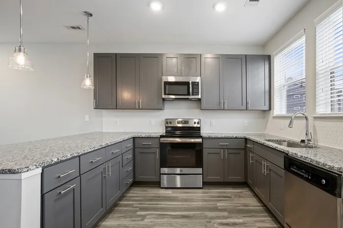 Kitchen at Lantower Garrison Park with wood-style flooring, granite countertops, tile backsplash, 10-foor ceilings, a kitchen island, and stainless steel, energy-efficient appliances.
