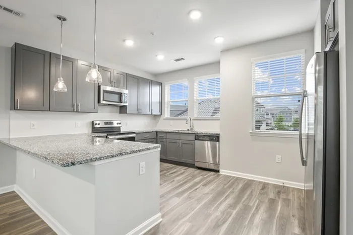 Kitchen at Lantower Garrison Park with wood-style flooring, granite countertops, tile backsplash, 10-foor ceilings, a kitchen island, and stainless steel, energy-efficient appliances.