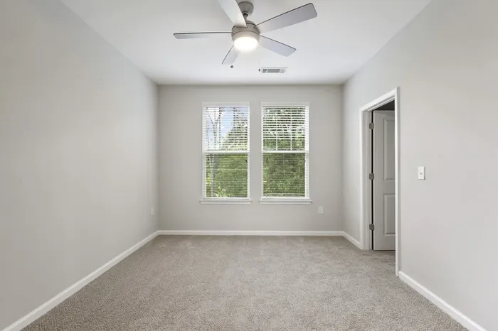 Carpeted bedroom at Lantower Garrison Park with two large windows and a ceiling fan.