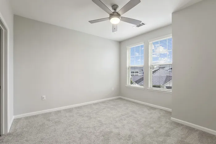 Carpeted bedroom at Lantower Garrison Park with two large windows and a ceiling fan.