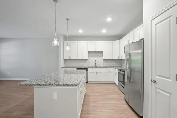 Kitchen at Lantower Garrison Park with wood-style flooring, granite countertops, tile backsplash, 10-foor ceilings, a kitchen island, and stainless steel, energy-efficient appliances.