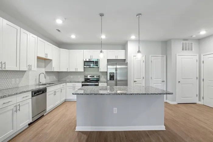 Kitchen at Lantower Garrison Park with wood-style flooring, granite countertops, tile backsplash, 10-foor ceilings, a kitchen island, and stainless steel, energy-efficient appliances.