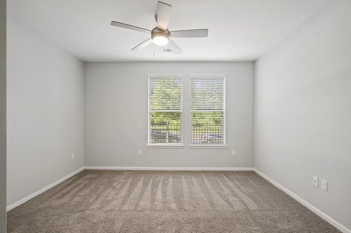 Carpeted bedroom at Lantower Garrison Park with two large windows and a ceiling fan.