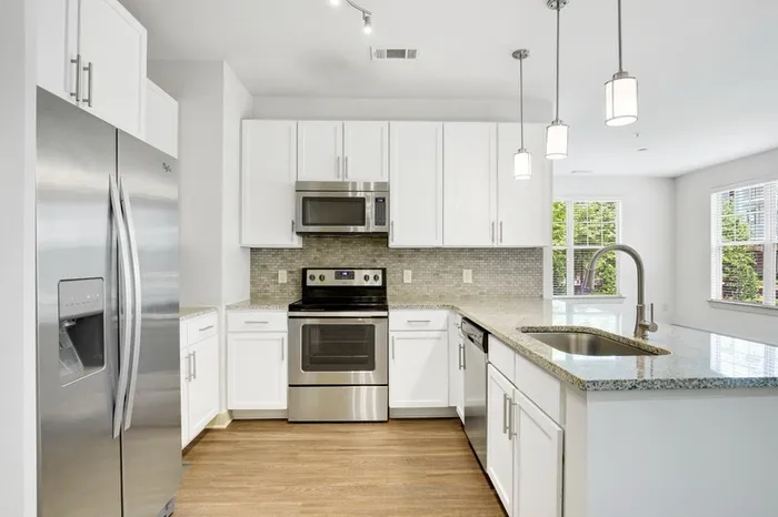 Kitchen at Lantower Waverly with wood-style flooring, granite countertops, tile backsplash, 10-foor ceilings, a kitchen island, and stainless steel, energy-efficient appliances.