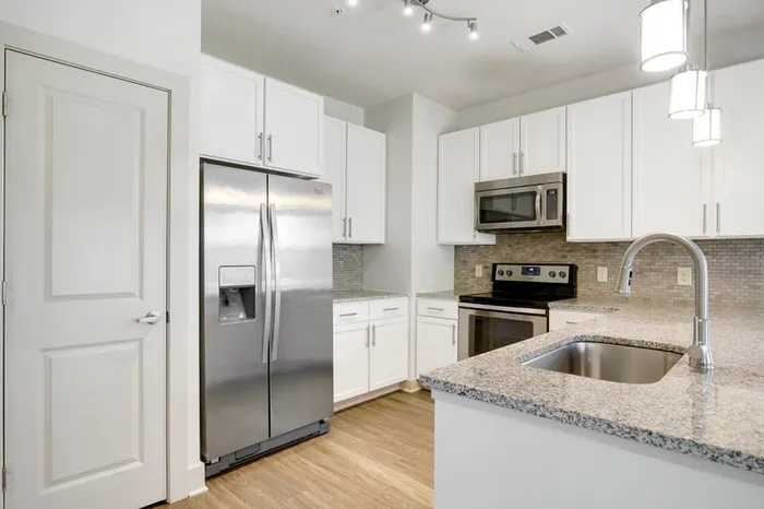 Kitchen at Lantower Waverly with wood-style flooring, granite countertops, tile backsplash, 10-foor ceilings, a kitchen island, and stainless steel, energy-efficient appliances.