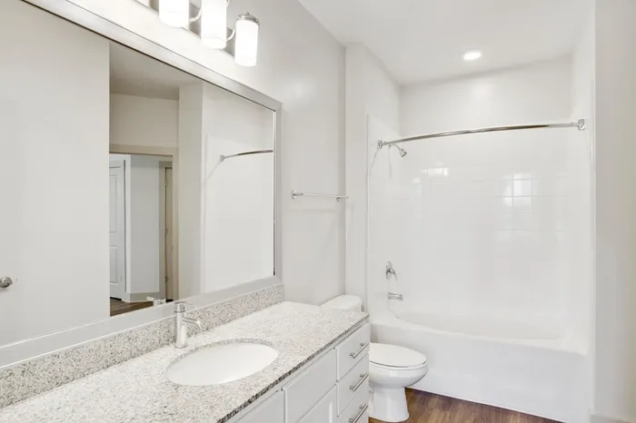 Bathroom at Lantower Waverly with granite countertops, a soaking tub and wood-style flooring.