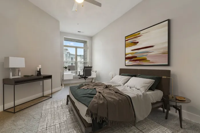 Carpeted bedroom with a large window, large wooden bed with cream and brown bedding, colorful wall art and access to a private balcony at Bullhouse.