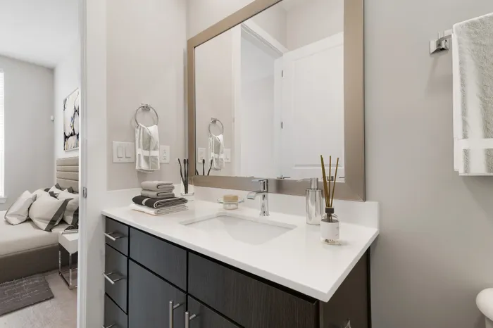 Modern bathroom with dark-colored cabinetry, white quartz countertops, 10-foot ceilings, brown countertop decorations and silver hardware at Bullhouse.