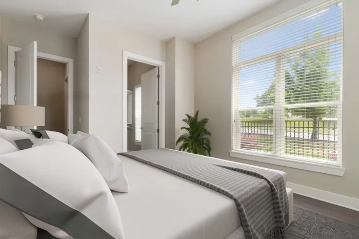 Bedroom with wood-style flooring, 10-foot ceilings, an expansive walk-in closet, a large floor-to-ceiling window with ample natural sunlight and a modern, grey and cream bed at Lantower Bullhouse.