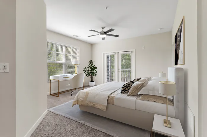 Carpeted living room with two large windows, 9-foot ceilings, access to a private balcony, modern furniture and a TV on a wooden stand at Realm at Patterson Place.
