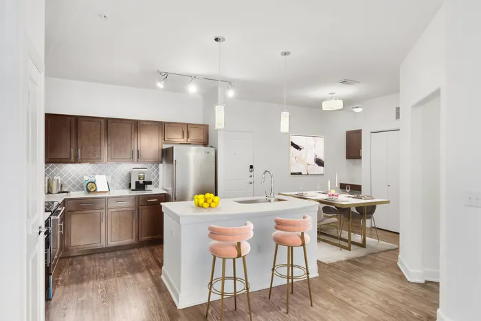 Modern kitchen fit with white center island, wood style flooring and cabinets, and ample lighting at Lantower Ambrosio.