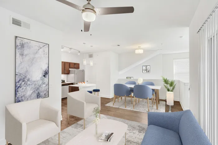 Spacious living room with ample room for seating, natural sunlight, and classic finishes with access to modern kitchen equipped with stainless steel appliances, large countertops, a floating island, and ample lighting at Lantower Ambrosio Apartments