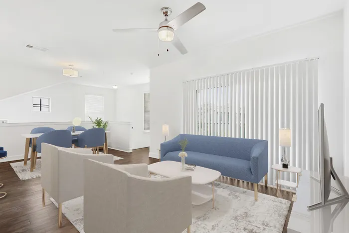 Spacious living room with ample room for seating, natural sunlight, and classic finishes, with access to private patio and stairs headed down at Lantower Ambrosio Apartments