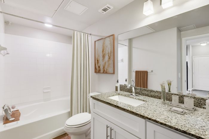 Apartment Bathroom with granite countertops and square tiled shower and tub, at Lantower Edgewater