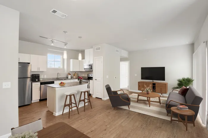 Apartment living room and kitchen with faux wood flooring, granite countertops, and Maytag stainless steel appliances at Lantower Edgewater