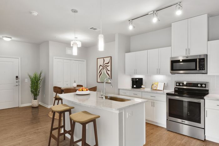 Kitchen and dining room with faux wood flooring, quartz countertops, and Maytag stainless steel appliances at Lantower Edgewater