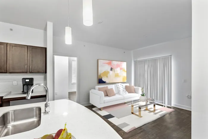 Modern kitchen fit with diamond white quartz countertops and stainless steel sink basin, stainless steel appliances, and an island with overhead lighting, sitting on vinyl plank flooring at Lantower Techridge apartments