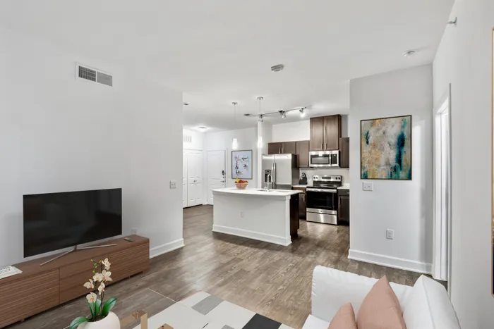Spacious living and dining room with room for plenty of furniture, connected to Modern kitchen fit with diamond white quartz countertops and stainless steel sink basin, stainless steel appliances, and an island with overhead lighting at Lantower Techridge