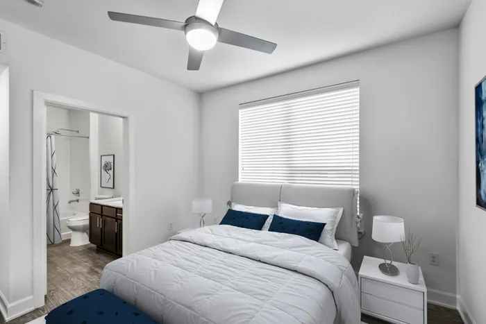 Bedroom and bathroom with vinyl plank flooring, pristine white walls, a large window for beautiful natural lighting and a ceiling fan for cooling in Lantower Techridge apartment