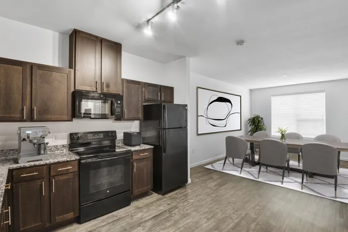 Open and spacious kitchen and living room with dark stained-wood cabinets, black stainless steel appliances, a large window for natural lighting and plenty of room for furniture at Lantower Techridge