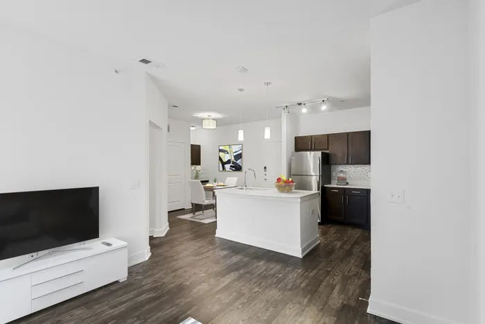 Spacious living and dining room with room for plenty of furniture, connected to Modern kitchen fit with diamond white quartz countertops and stainless steel sink basin, stainless steel appliances, and an island with overhead lighting at Lantower Techridge