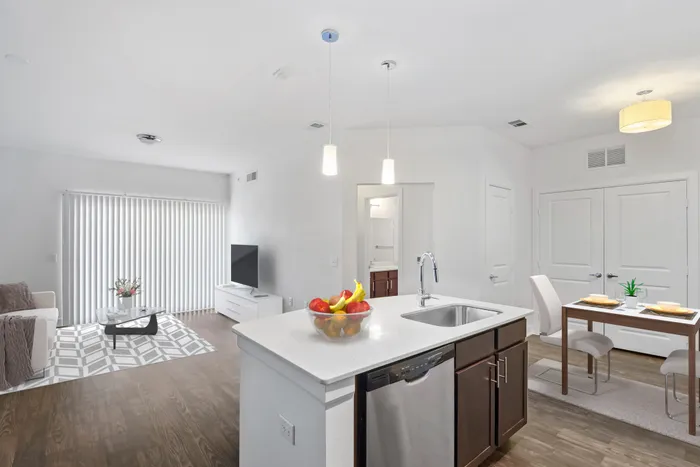 Spacious living and dining room with room for plenty of furniture, connected to Modern kitchen fit with diamond white quartz countertops and stainless steel sink basin, stainless steel appliances, and an island with overhead lighting at Lantower Techridge