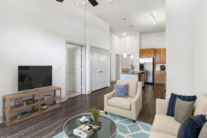 Room and kitchen with granite countertops, wood-style cabinets, stainless steel appliances, and a kitchen island in the middle at Lantower Legacy Lakes apartments