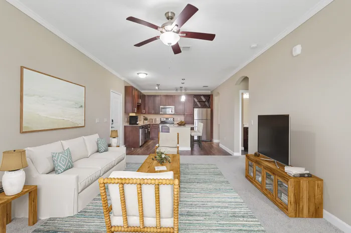 A carpeted living room and a kitchen with wood-style floors and espresso wood cabinetry at Lantower Grande Pines decorated with wooden, modern furniture and blue accents.