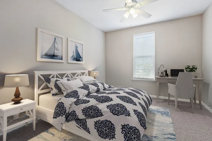 Carpeted bedroom with a large window, a large white bed with blue decorations, a simple, modern desk with a cream chair in the corner and blue wall art at Lantower Asturia.
