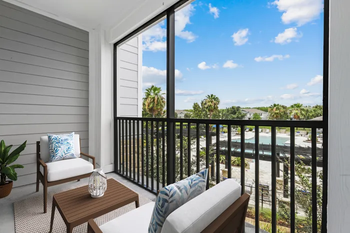 Balcony with a view of the resort-style pool and palm trees with dark-colored, wooden furniture with cream cushions and blue throw pillows at Lantower Asturia.