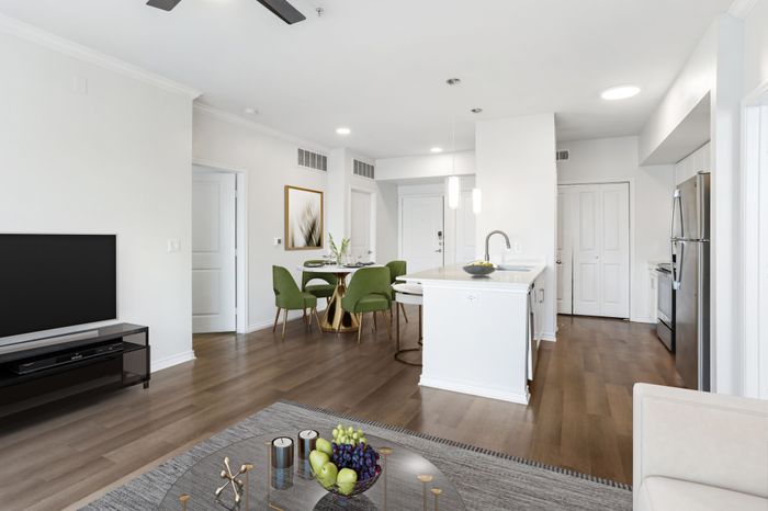 Spacious living and dining room with room for plenty of furniture, connected to Modern kitchen fit with white countertops and stainless steel sink basin, stainless steel appliances, and an counter with overhead lighting at Lantower Residences at the Collect