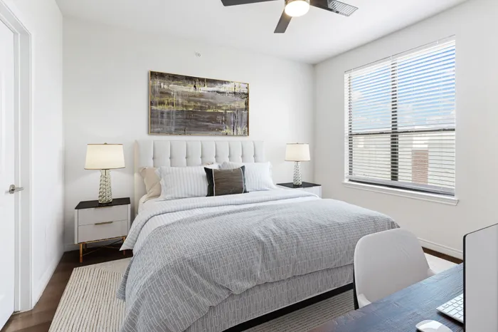 Spacious bedroom with lots of room for furniture, has a dark wood-style ceiling fan, large window for natural lighting, and hardwood flooring at Lantower Residences at the Collection