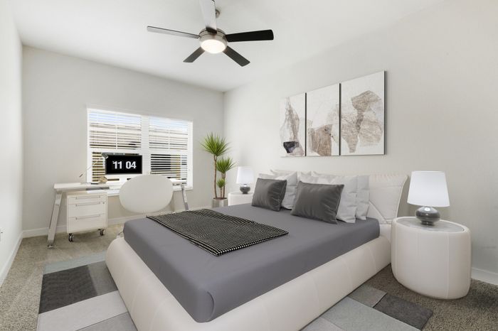 Spacious, carpeted bedroom with a ceiling fan, two large windows with ample natural light, modern, cream furniture with grey accents and grey wall art at Lantower Brandon Crossroads.