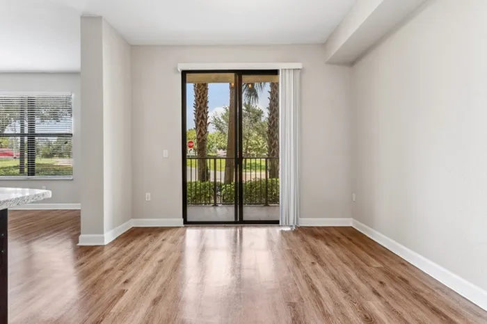 Open-concept dining room with view of kitchen and living area and a large sliding door proving ample natural light leading out to private patio at Lantower Westshore.