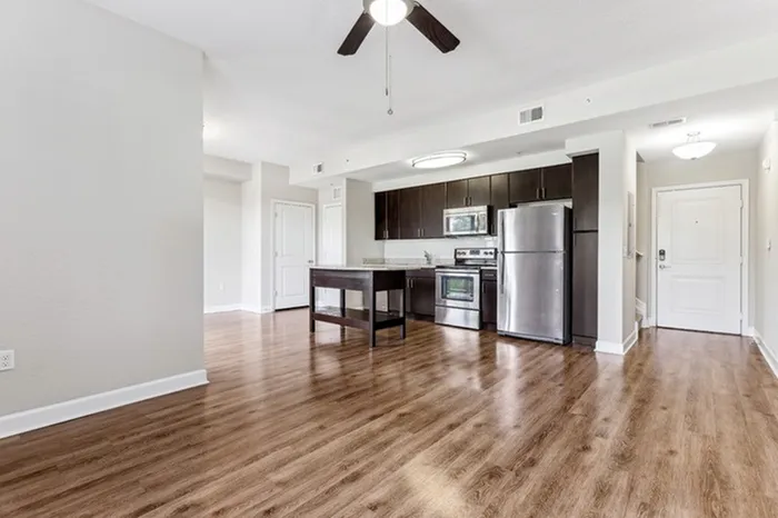 Spacious open-concept living area with view of kitchen and dining room, wood-style flooring, ceiling fan, and ample natural light at Lantower Westshore.